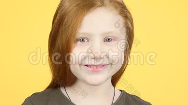 特写红发儿童对着黄色背景的镜头微笑。 慢动作